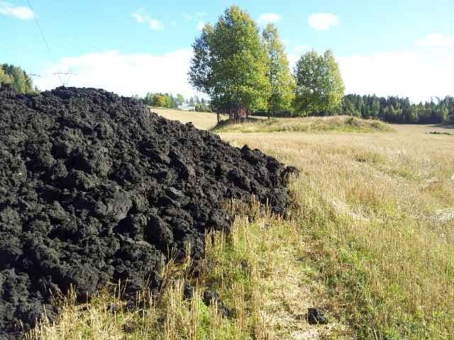 Levering av en stor mengde biorest på en åker. Foto. 